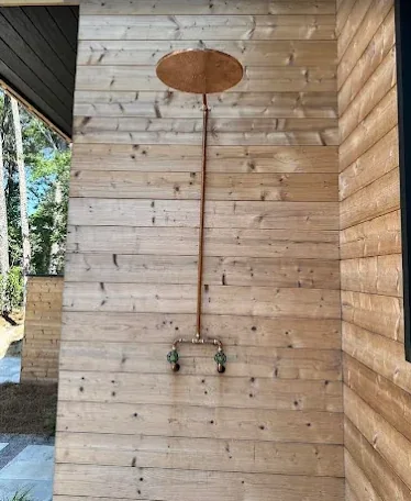 Custom copper rainfall shower installed on a cedar exterior wall